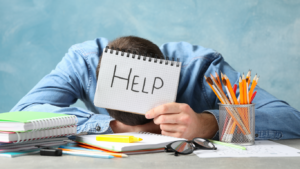 Exhausted boy on deck holding a help sign, illustrating trauma and burnout connection.