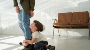 Child clinging to caregiver’s leg, illustrating attachment wounds and early emotional distress.